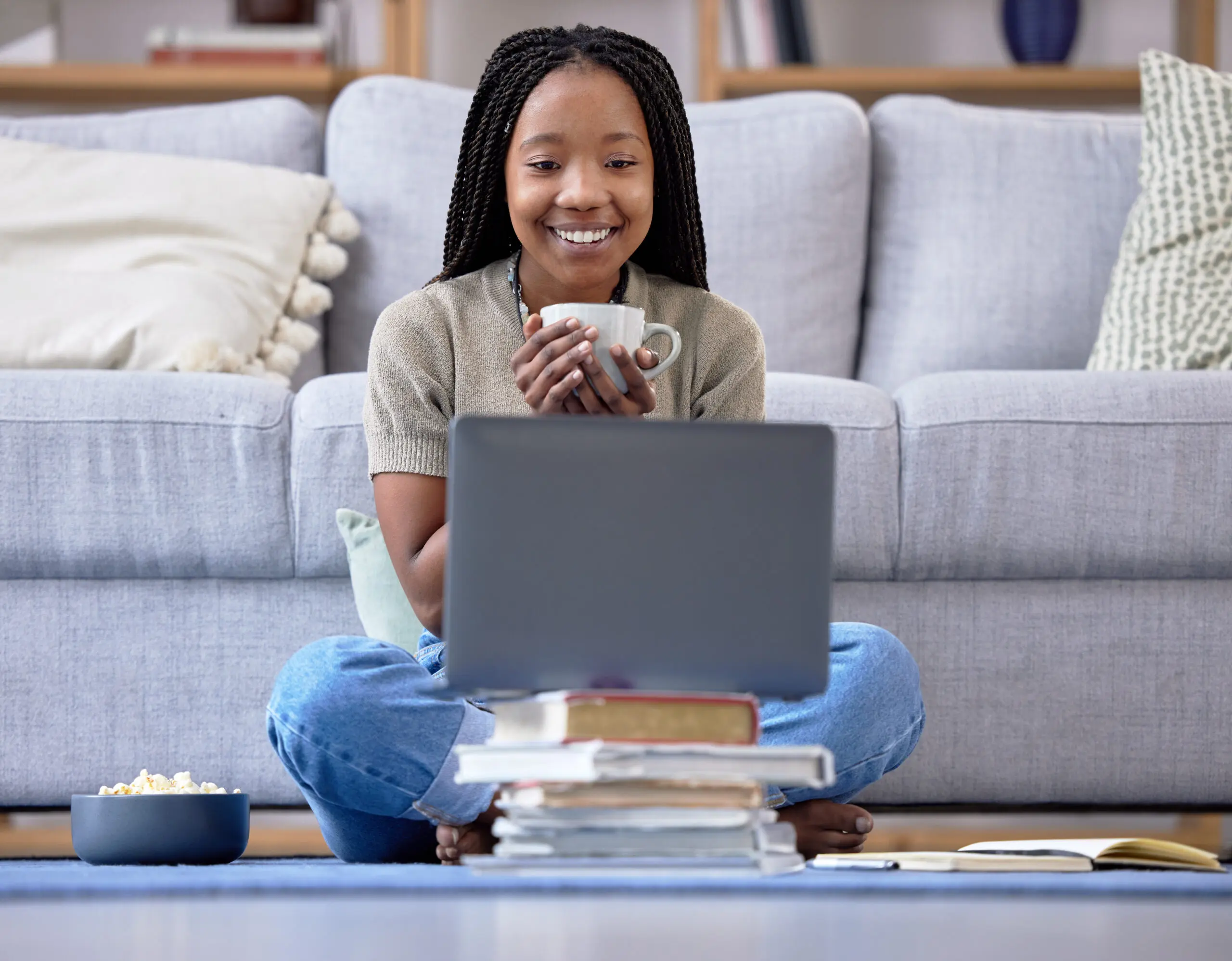 Coffee, student and laptop for girl in living room, happy and relax while streaming in her home. Tea, books and break in distance learning, remote or homeschool for teenage female with online class.